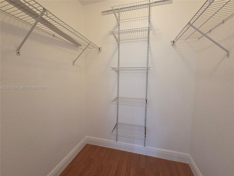 Walk-in closet featuring wood-finish flooring and integrated white wire shelving systems