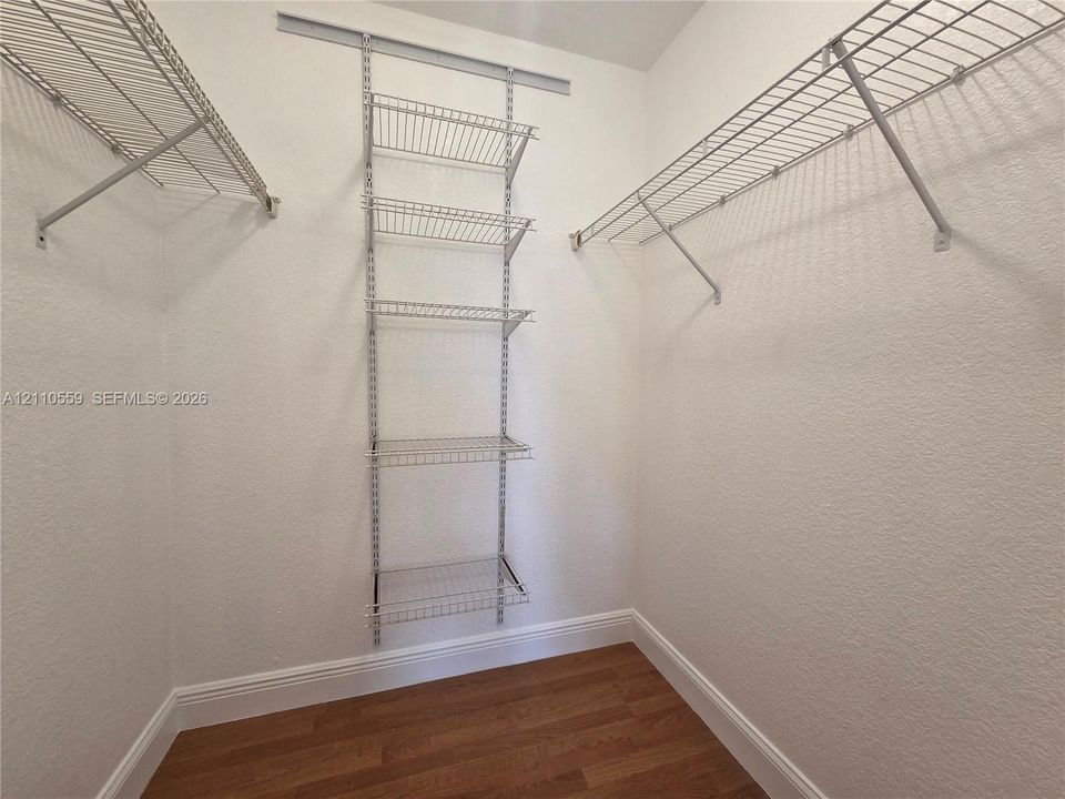 Walk-in storage space featuring wood-finish flooring and wall-mounted wire shelving units