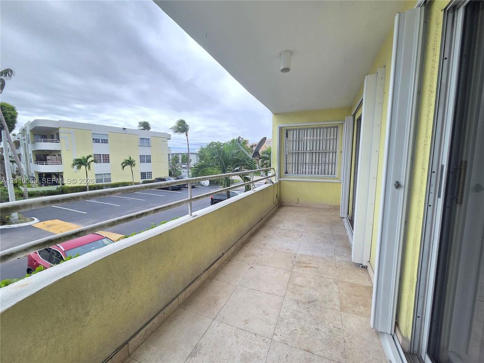 Covered balcony featuring stone-tile flooring, metal railings, and recessed ceiling lighting