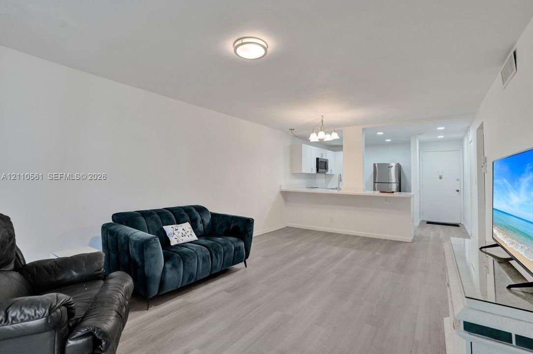Open-concept area featuring wood-finish flooring, a breakfast bar, recessed lighting, and white cabinetry