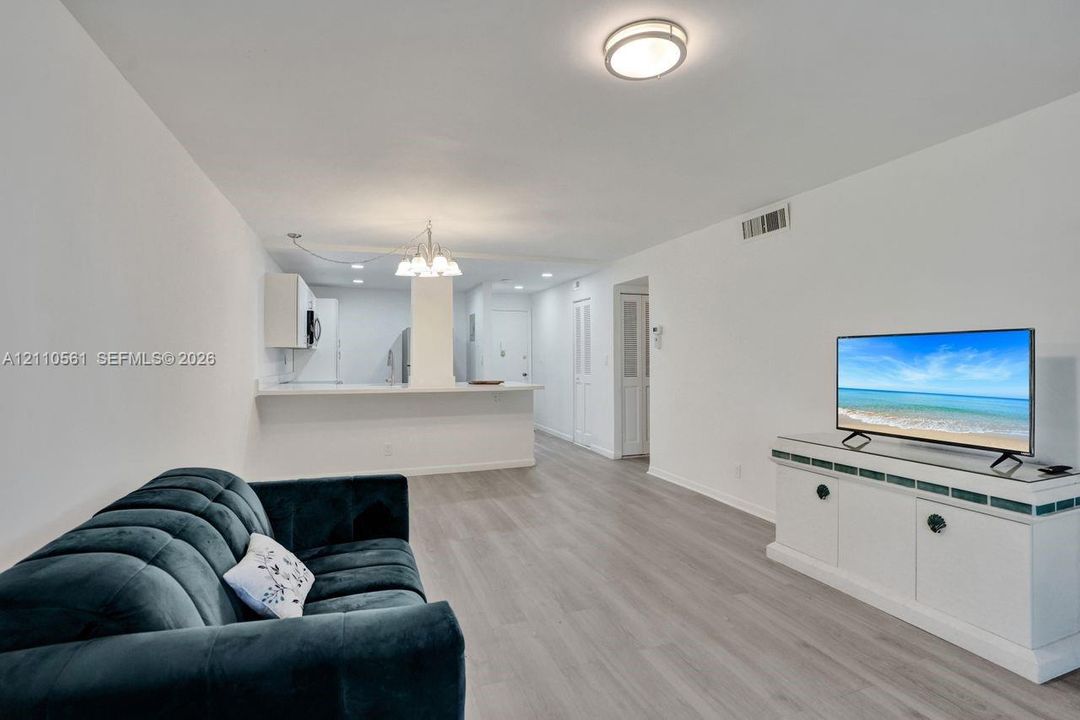 Open-concept floor plan featuring wood-finish flooring, a breakfast bar, recessed lighting, and a decorative chandelier