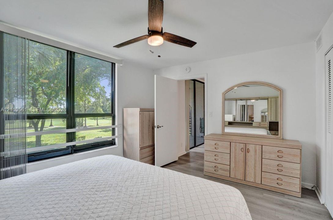 Floor-to-ceiling windows, wood-finish flooring, and a ceiling fan with integrated lighting