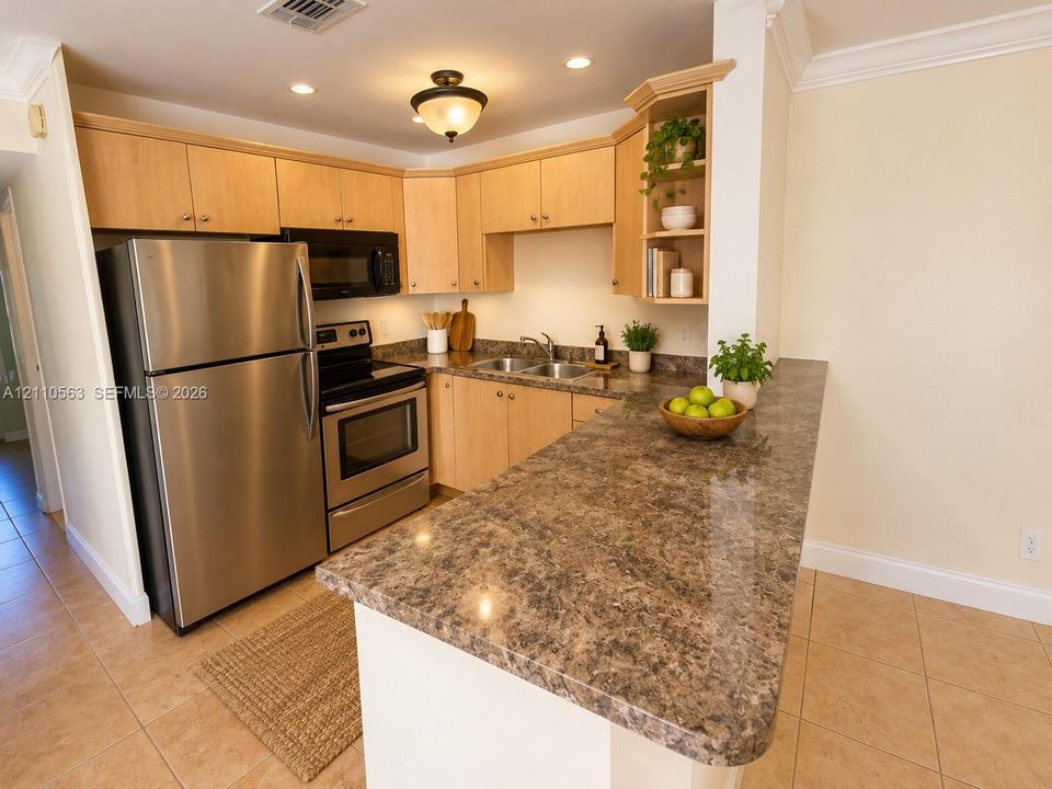 Kitchen featuring wood cabinetry, stainless steel appliances, a peninsula with stone-finish countertops, ceramic tile flooring, and recessed lighting