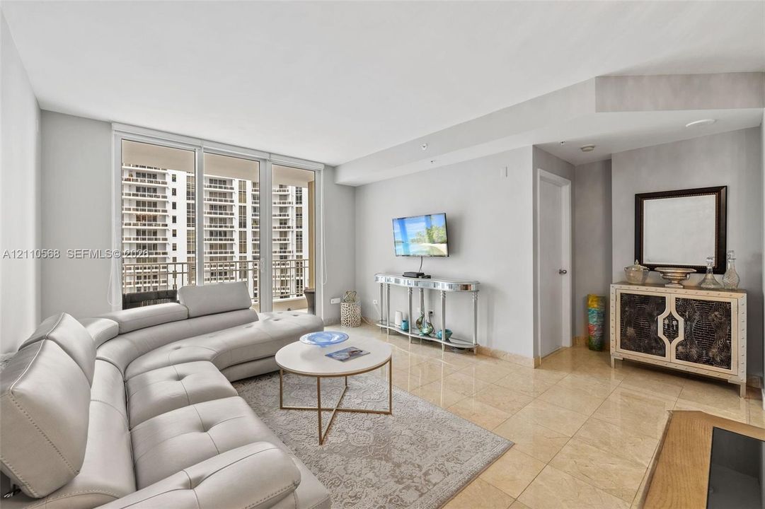 Living area featuring floor-to-ceiling glass sliding doors, stone tile flooring, and neutral wall tones