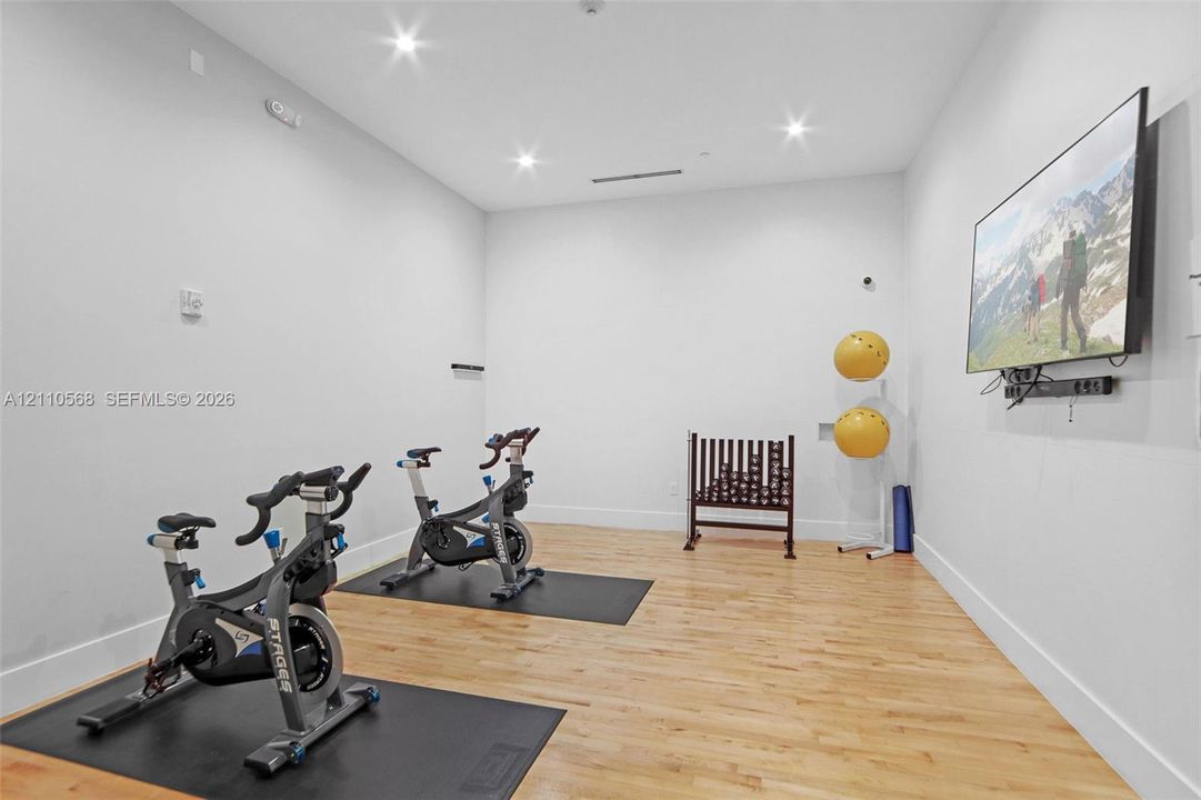 Interior space featuring light-toned wood-finish flooring, recessed ceiling lighting, and a wall-mounted display screen