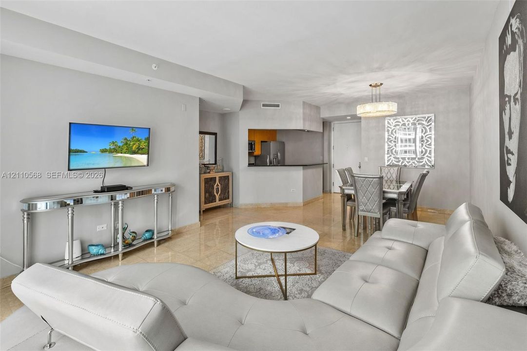 Open-concept interior featuring large-format stone flooring, neutral wall tones, and a pass-through kitchen counter