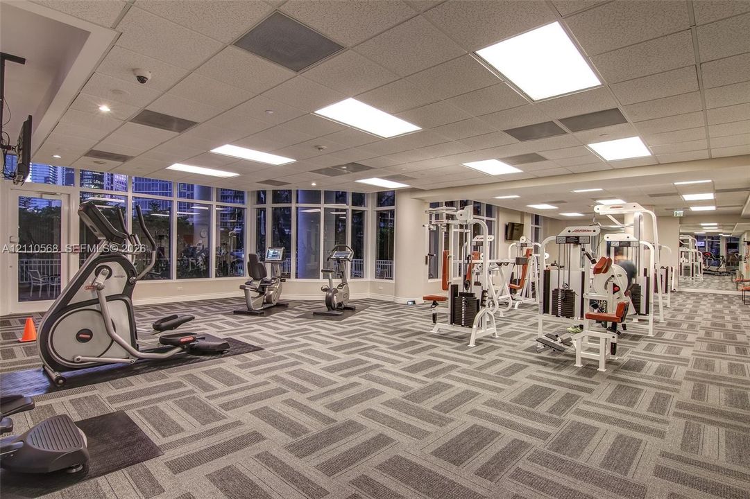 Fitness center featuring floor-to-ceiling windows, patterned carpeting, and recessed ceiling lighting