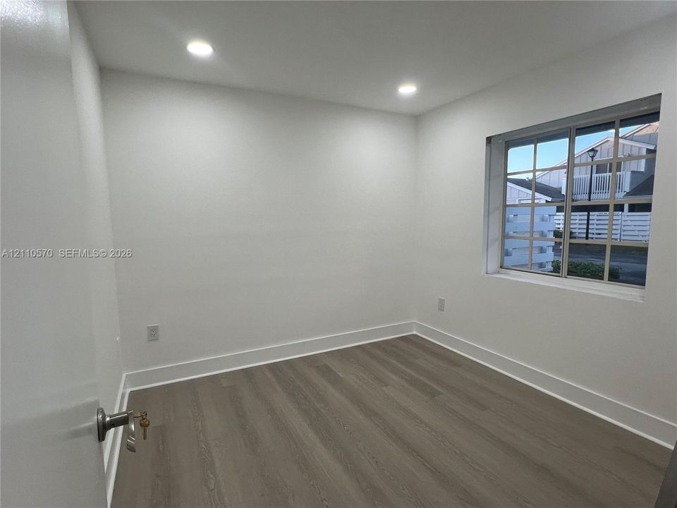 Neutral-toned wood-finish flooring, recessed lighting, and a multi-pane window