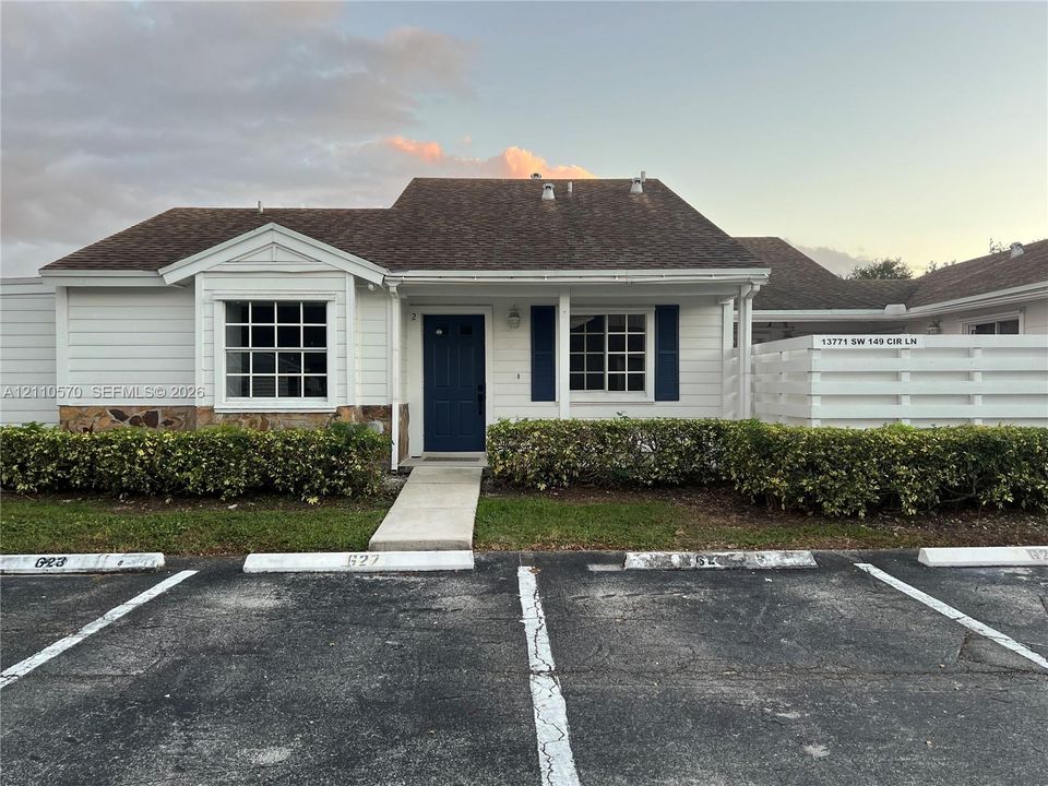 Single-story residence featuring horizontal lap siding, stone veneer base, pitched roof, and a covered front entryway with a paneled door
