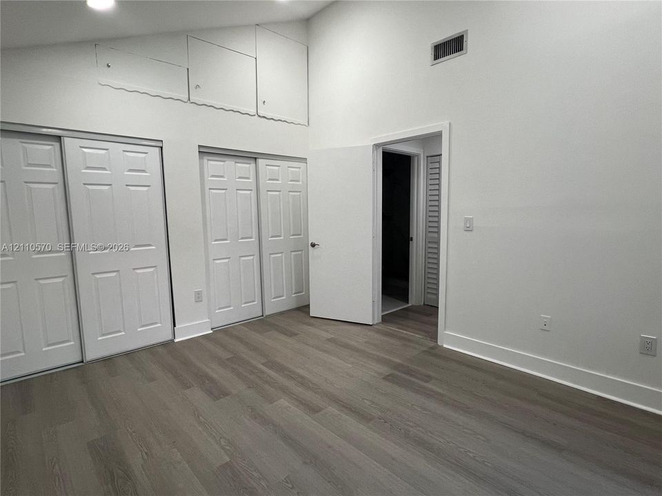 Vaulted ceilings, wood-finish flooring, recessed lighting, and multiple interior closets featuring paneled doors