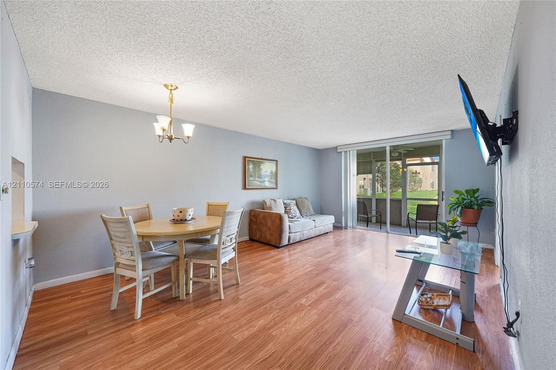 Living area featuring wood-finish flooring, a multi-arm chandelier, and sliding glass doors leading to a screened patio