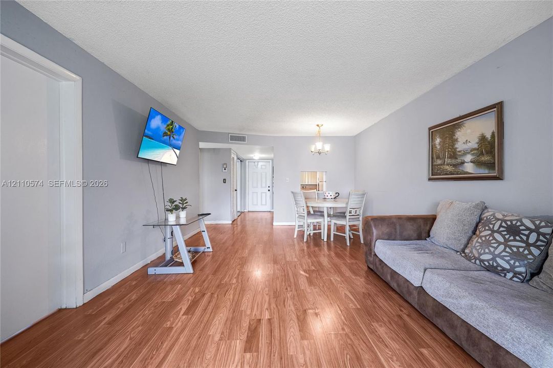 Living space featuring wood-finish flooring, a neutral color palette, and a multi-arm chandelier