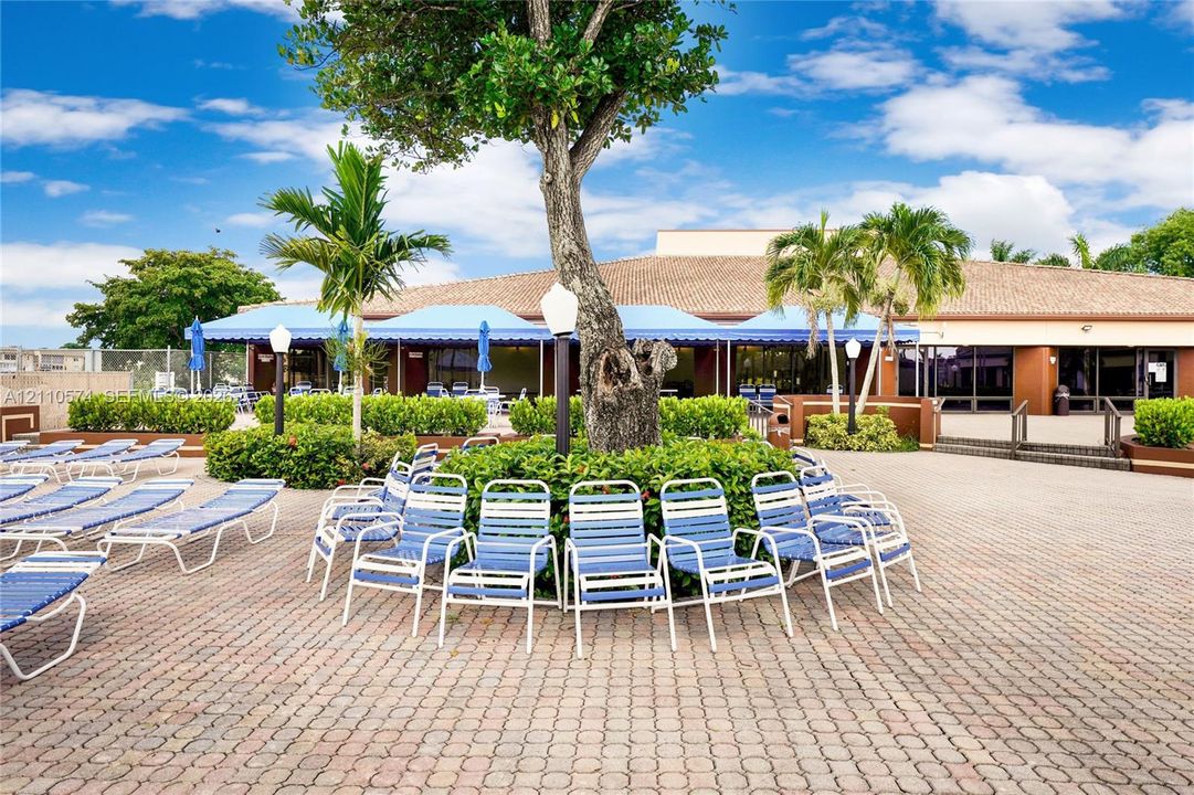 Extensive brick-paver patio area featuring mature landscaping, integrated lighting fixtures, and a covered terrace