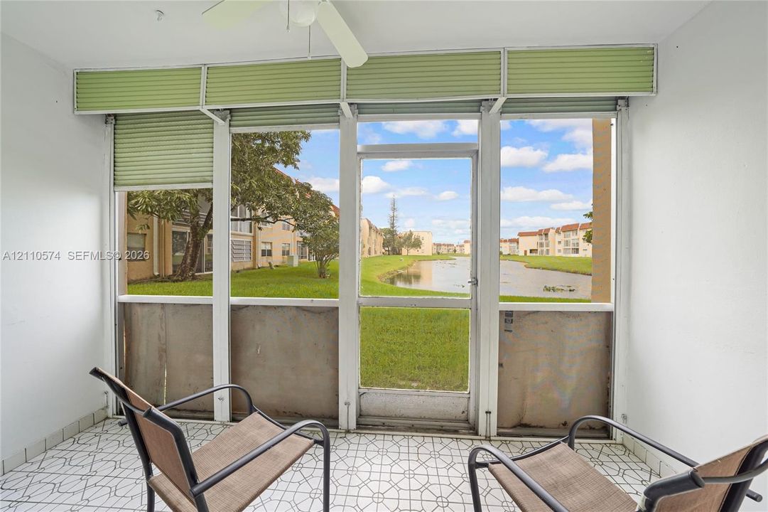 Enclosed porch featuring geometric tile flooring, ceiling-mounted fan, and floor-to-ceiling screen panels