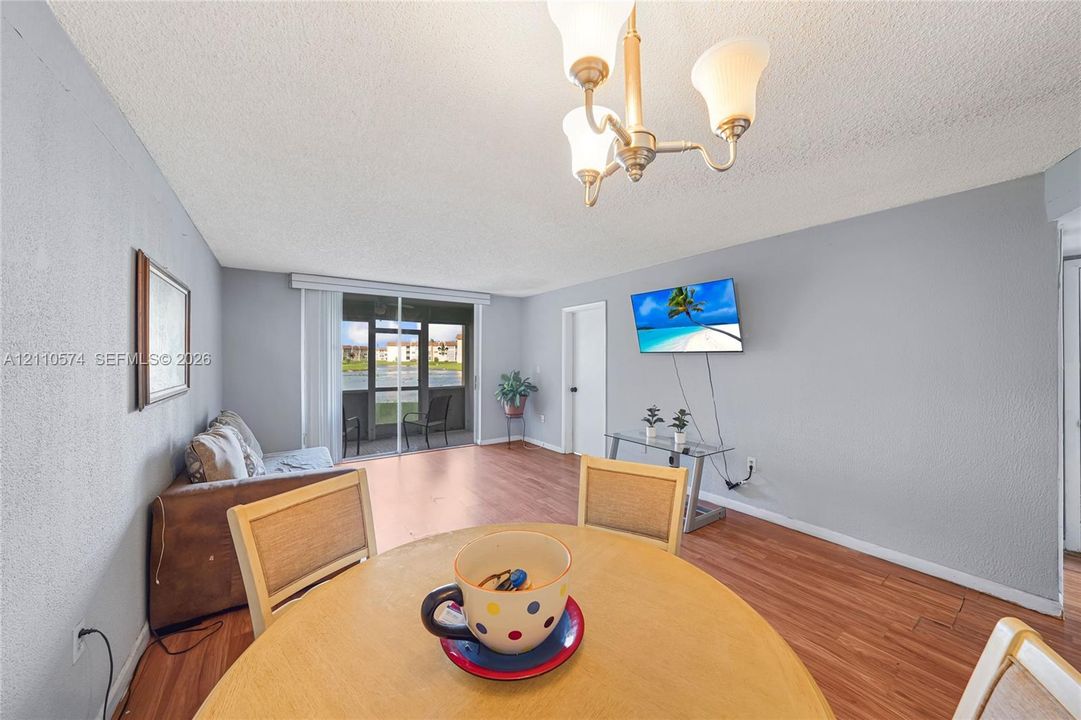 Living area featuring wood-finish flooring, a multi-arm chandelier, and sliding glass doors opening to a screened-in balcony