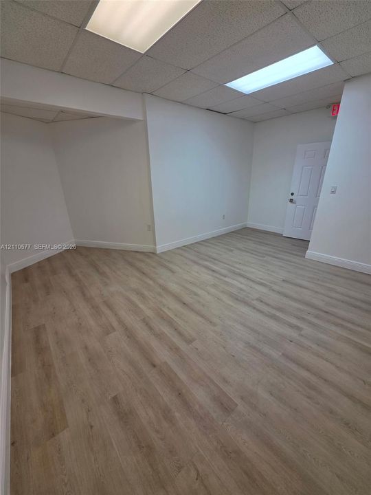 Interior space featuring neutral wall paint, wood-finish flooring, and recessed ceiling tile lighting