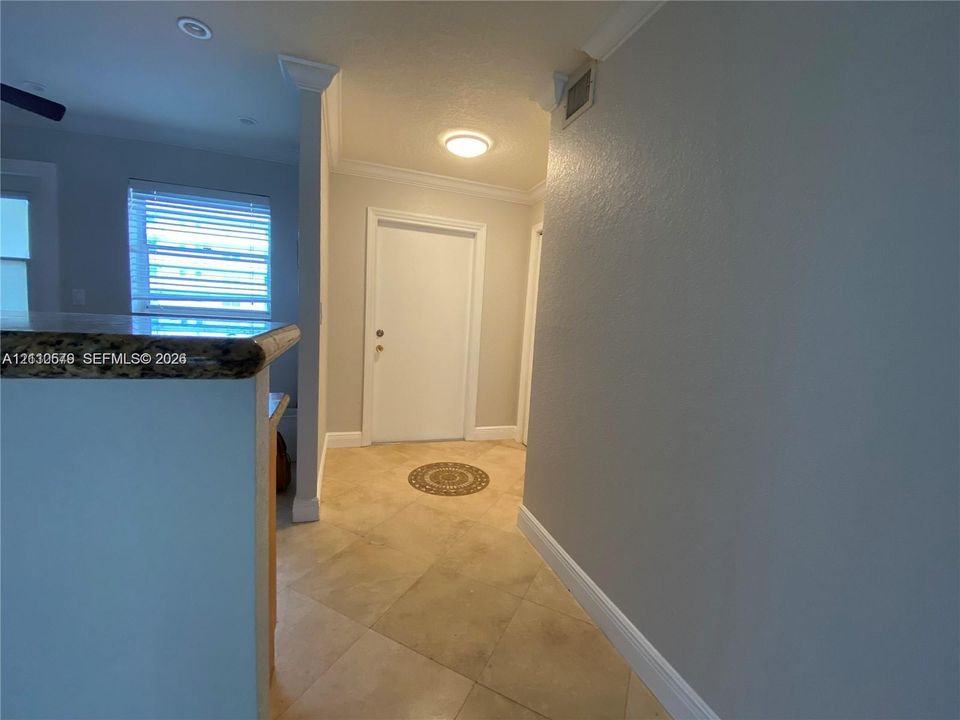 Entryway featuring tile flooring, crown molding, and a solid-panel door with architectural casing