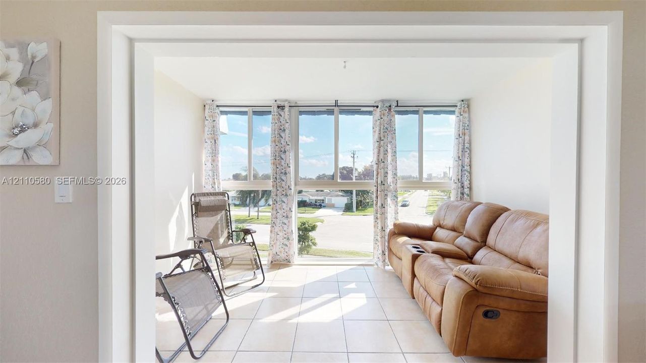 Sunroom featuring large windows, ceramic tile flooring, and a wide entryway