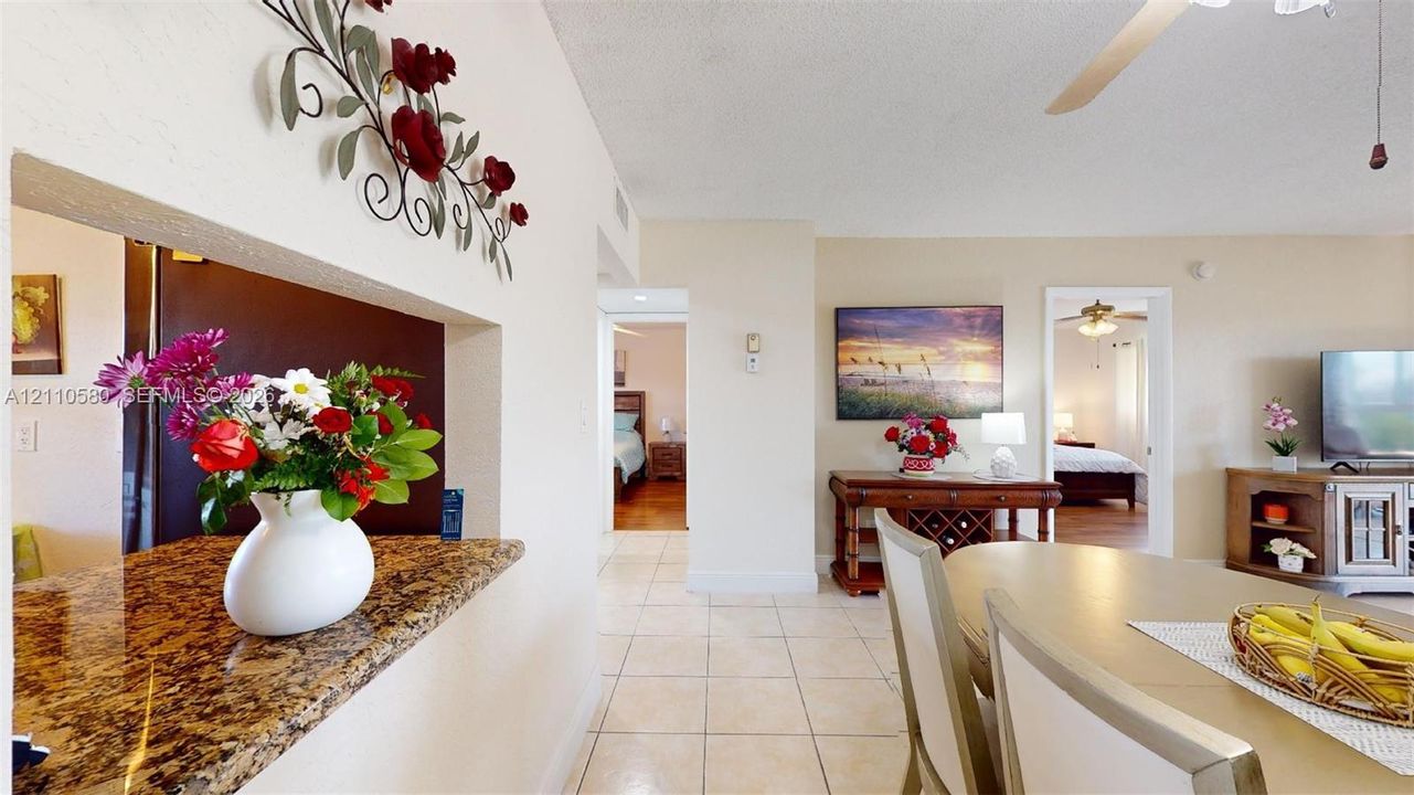 Neutral stone-surface breakfast bar, ceramic tile flooring, and ceiling fan