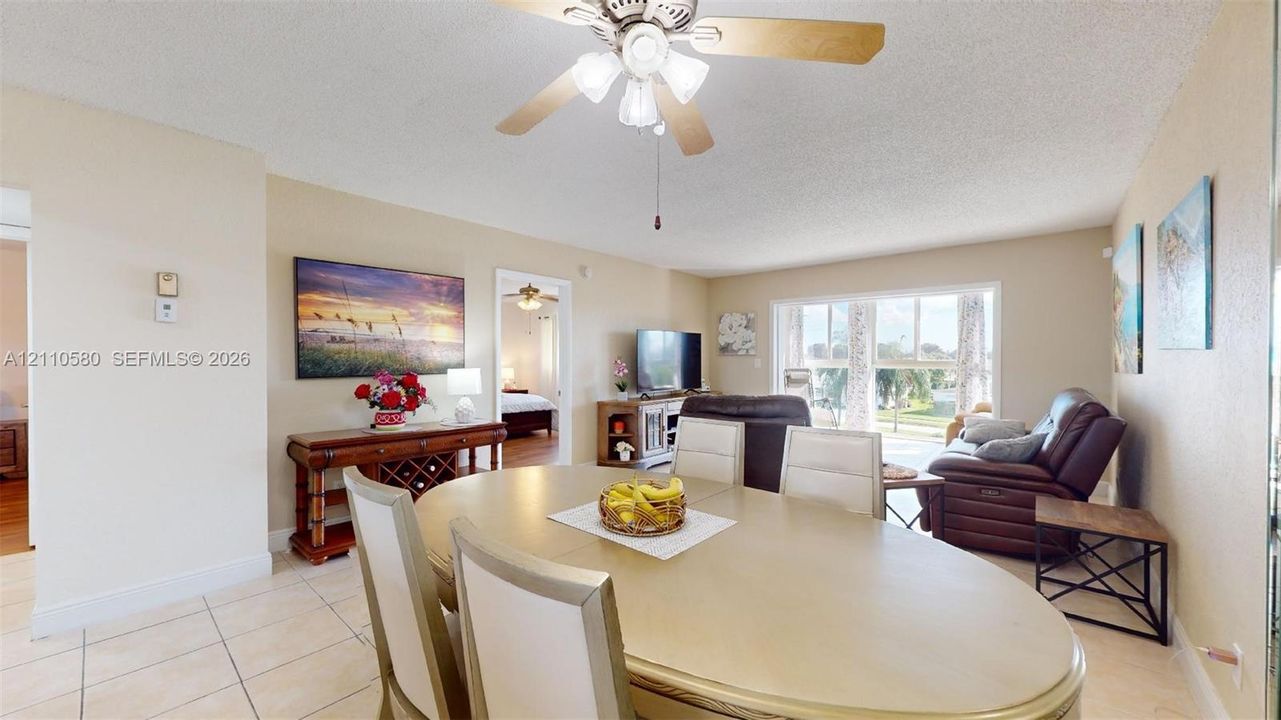 Neutral tile flooring, ceiling fan with light fixture, and floor-to-ceiling windows