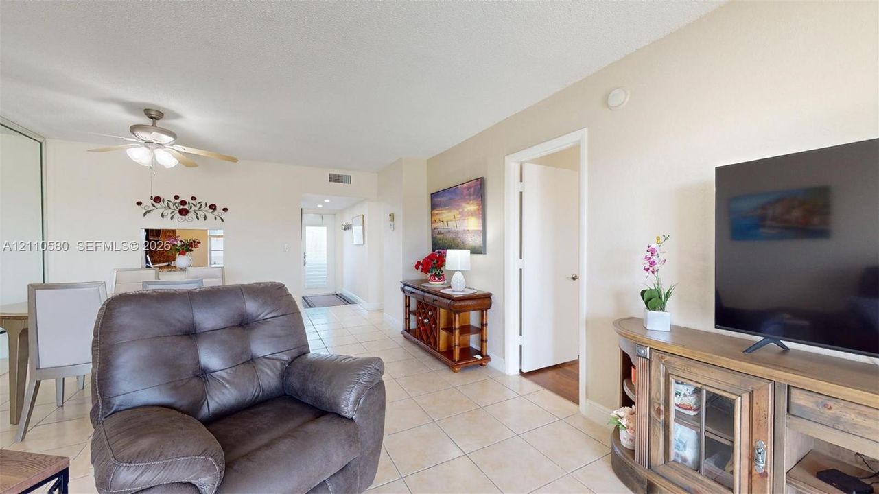 Neutral-tone walls, large-format tile flooring, and a ceiling fan with integrated lighting