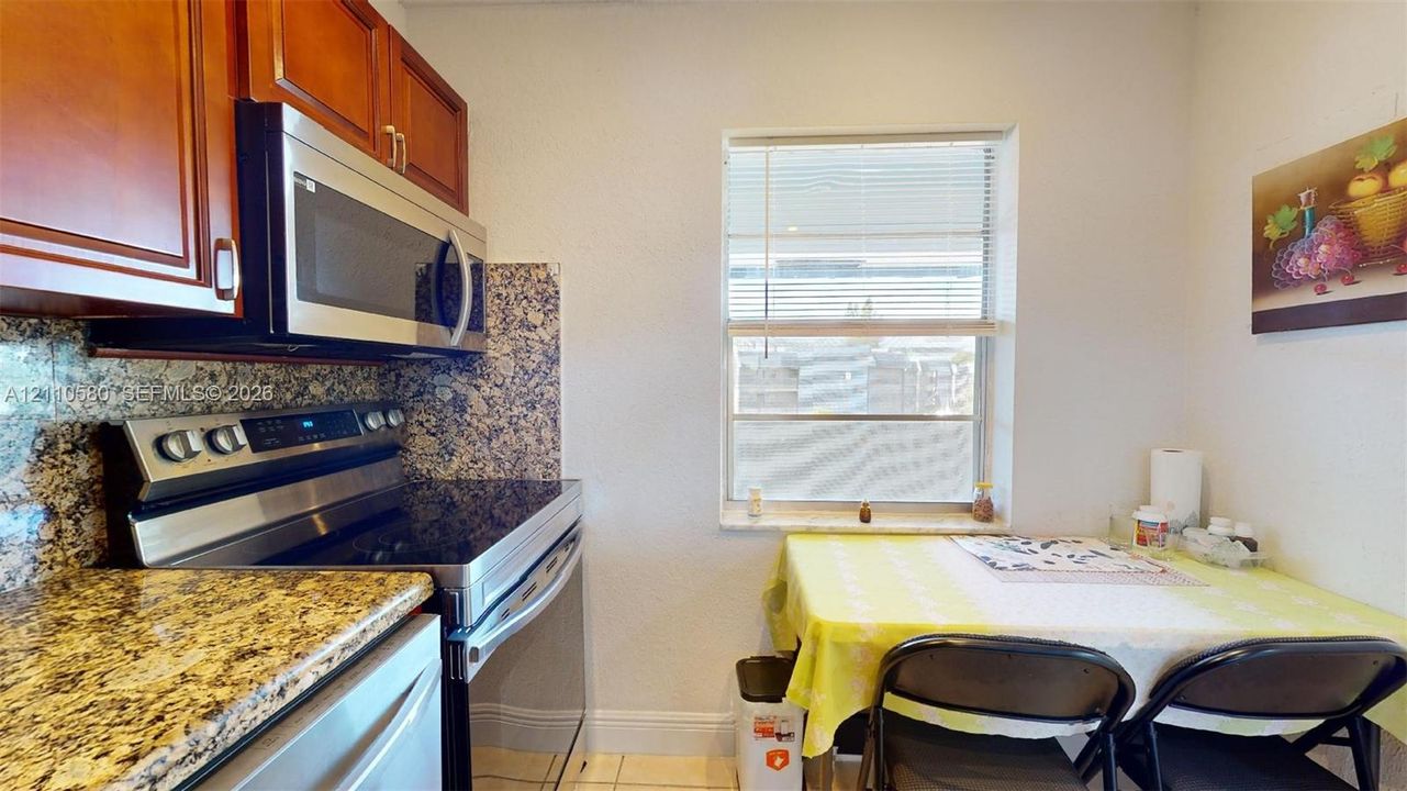 Kitchen featuring wood cabinetry, stone countertops, stone backsplash, and stainless steel appliances