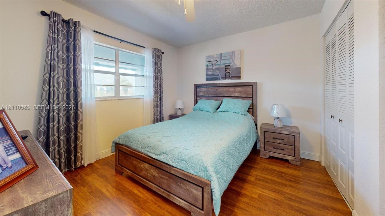 Wood-finish flooring, white louvered closet doors, and a ceiling fan