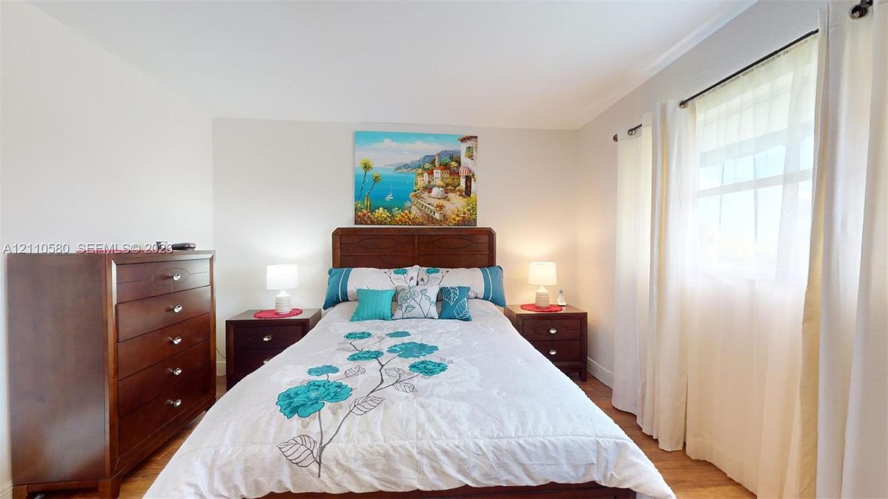 Neutral wall paint, wood-finish flooring, and natural lighting provided by window coverage