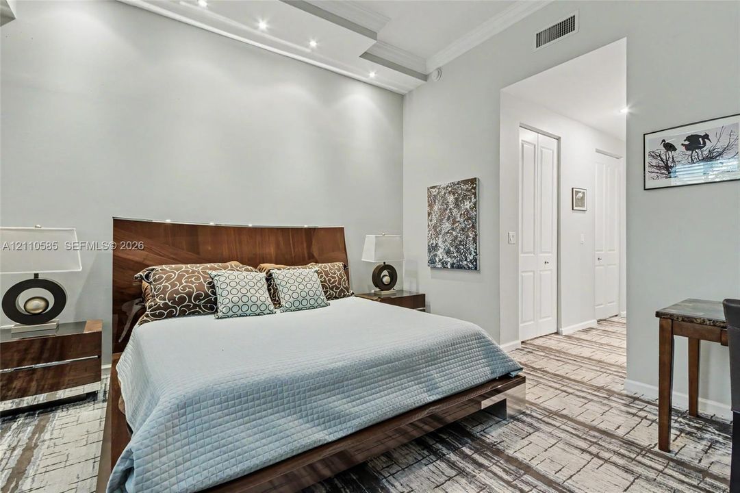 Main Bedroom. Tray ceiling featuring integrated recessed lighting, neutral wall palette, and patterned floor covering