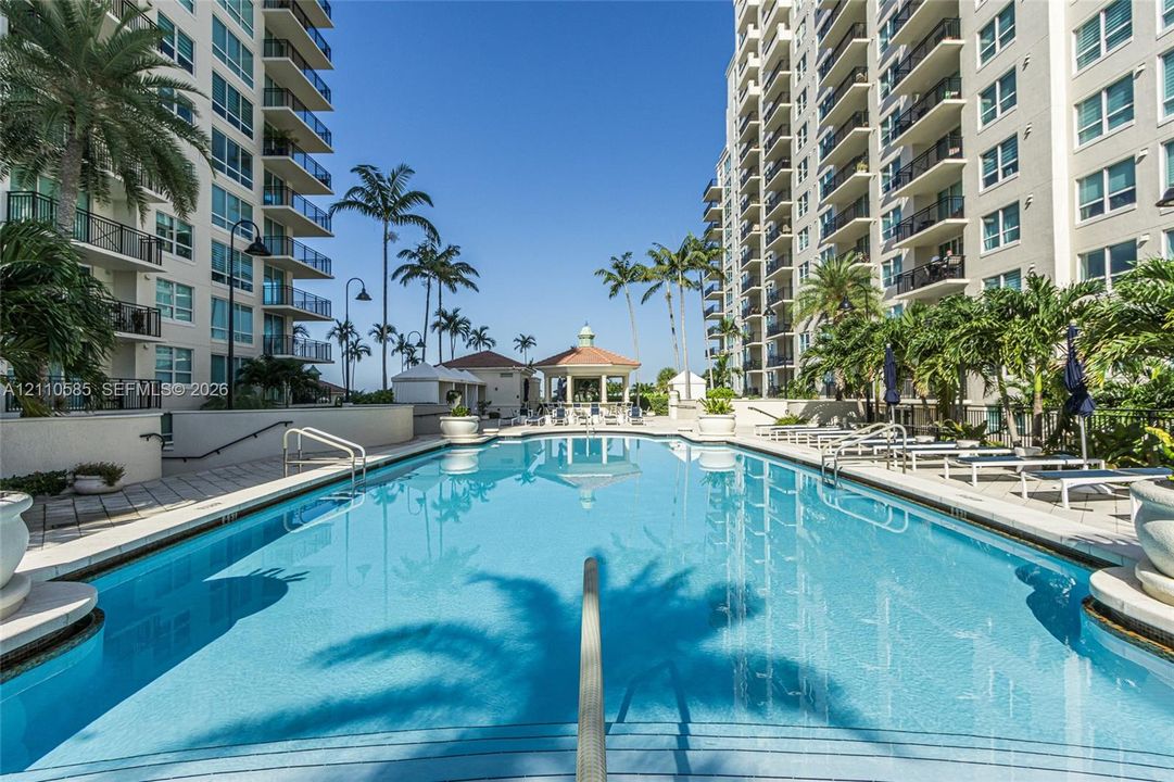 Swimming pool with a paved deck, metal railings, and a central gazebo