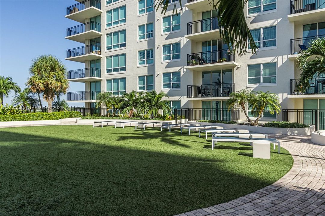 Green space featuring artificial turf with seating to relax