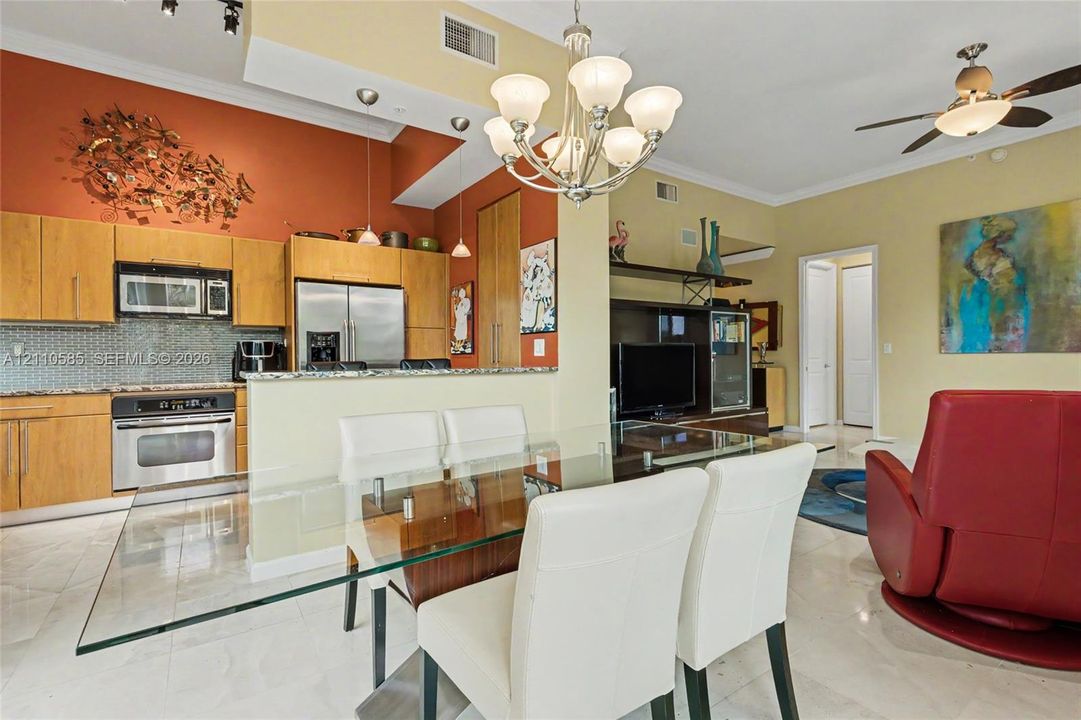 Kitchen featuring wood cabinetry, stone countertops, glass tile backsplash, stainless steel appliances, and pantry.
