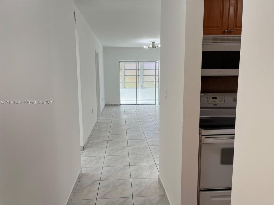 Interior featuring tile flooring throughout, white cabinetry, built-in microwave, range oven, and sliding glass door