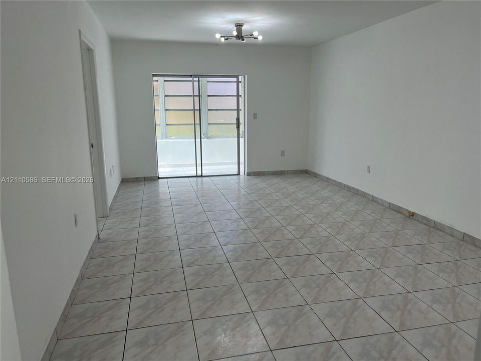 Interior space featuring large-format ceramic tile flooring, neutral walls, multi-pane sliding glass doors, and a multi-light flush-mount ceiling fixture