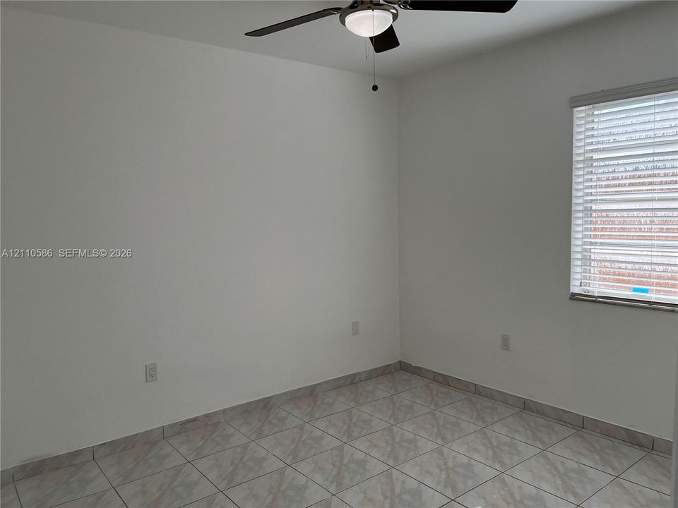 Interior space featuring ceramic tile flooring, a multi-blade ceiling fan with integrated light fixture, and horizontal window blinds