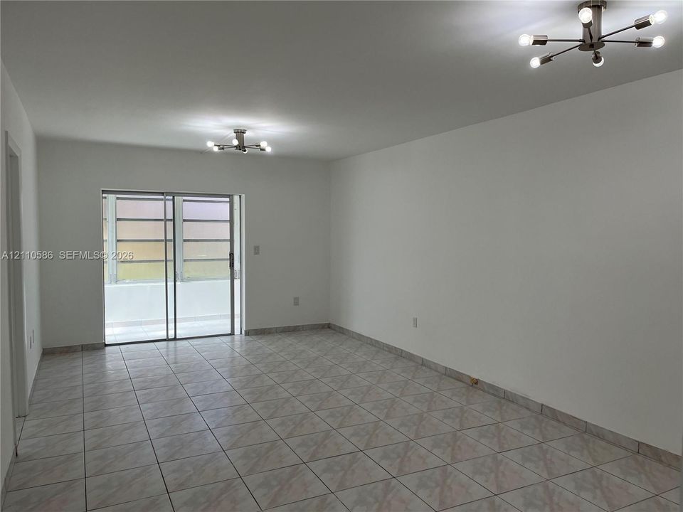 Interior space featuring tile flooring, dual multi-arm sputnik-style ceiling light fixtures, and a glass sliding door