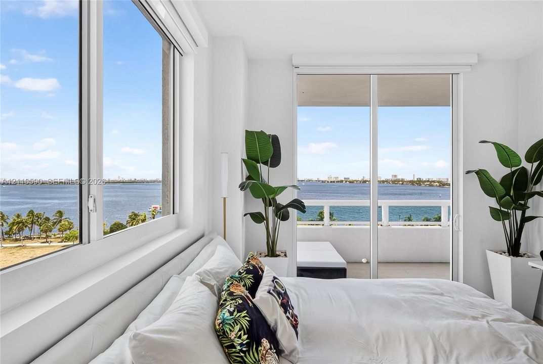 Floor-to-ceiling windows, sliding glass door, private balcony with railing, and expansive water exposure