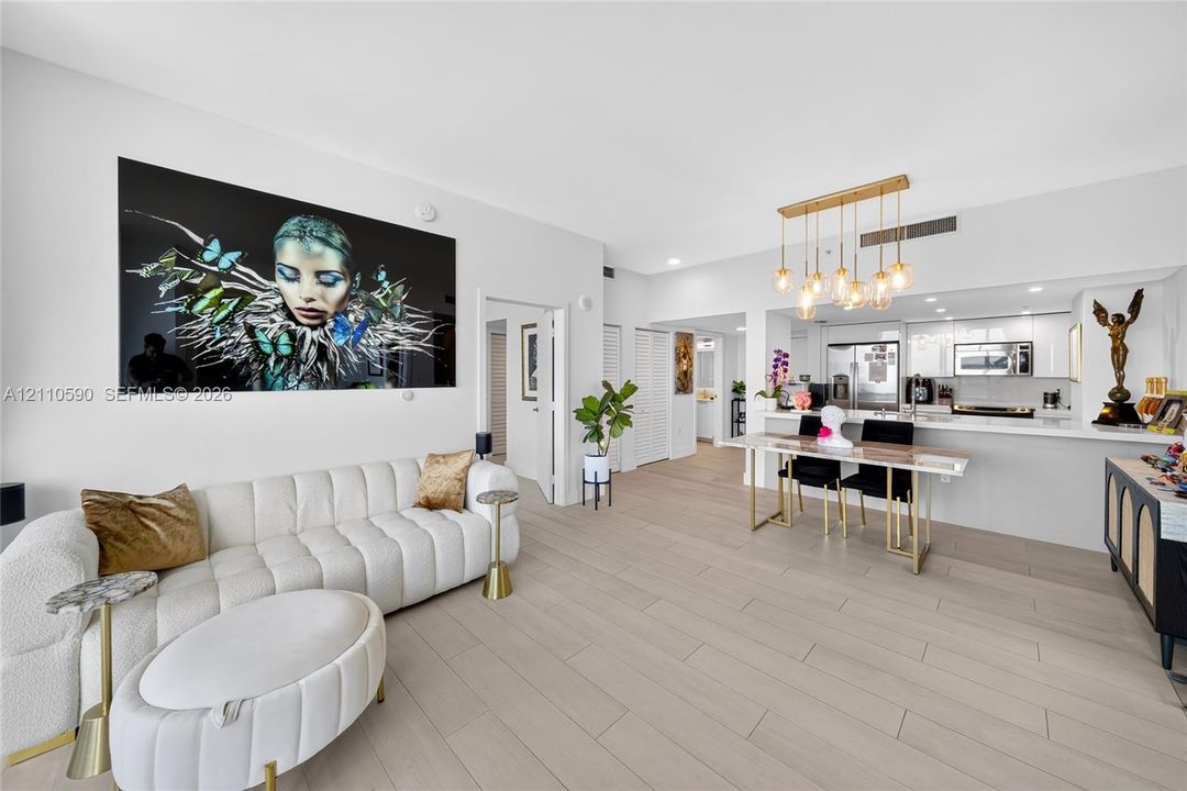 Open-concept interior featuring large-format tile flooring, recessed lighting, and a multi-pendant brass light fixture