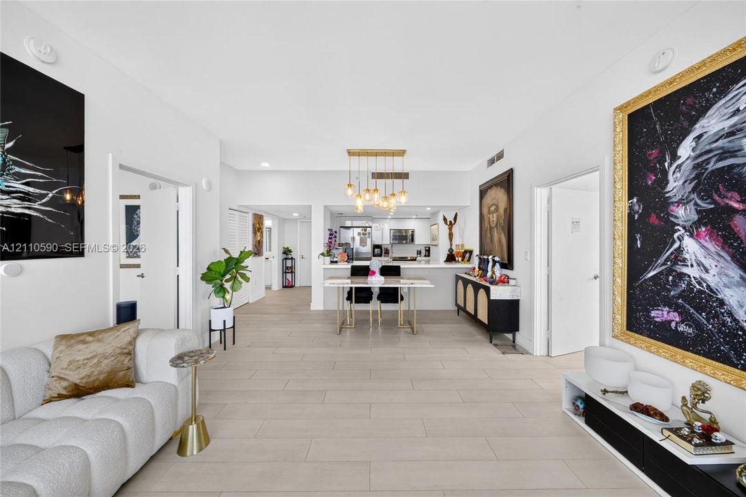 Open-concept interior featuring oversized tile flooring, recessed lighting, and a multi-pendant gold-tone light fixture