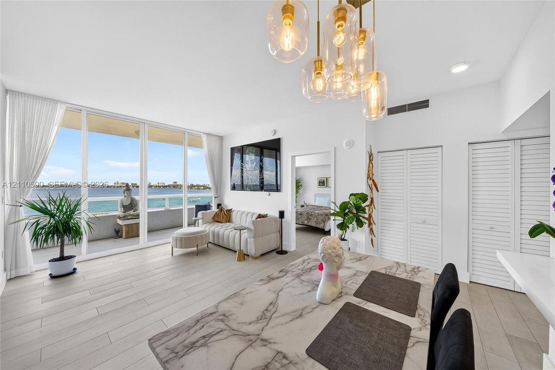 Floor-to-ceiling glass sliding doors, custom multi-pendant brass light fixture, wood-finish tile flooring, and louvered closet doors