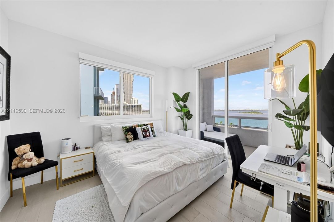 Bright room featuring floor-to-ceiling glass sliding doors, wood-finish flooring, and large windows with water and skyline scenery