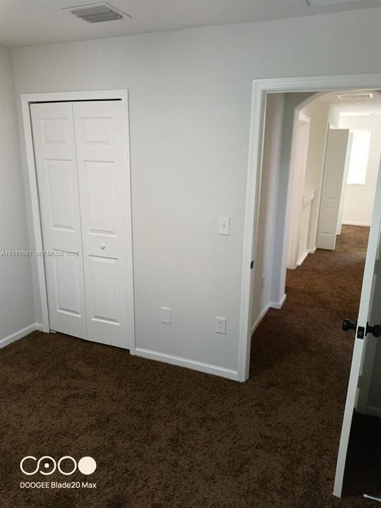 Room featuring neutral wall tones, textile flooring, and white paneled bi-fold closet doors