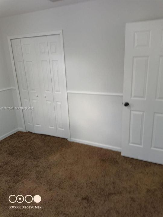 Interior space featuring mid-tone carpeting, chair rail molding, and a bi-fold closet with six-panel doors