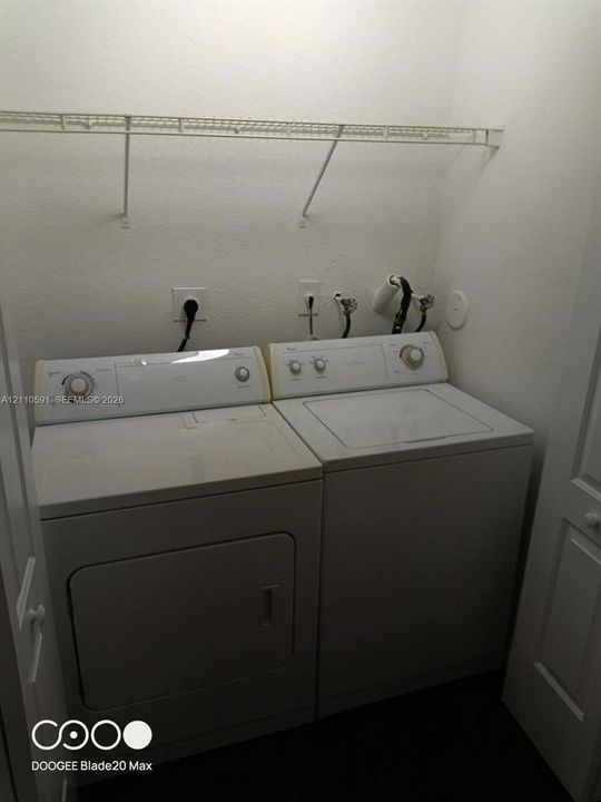 Laundry area featuring a dedicated washer and dryer hookup, white top-load washer, front-load dryer, and an installed wire shelving unit