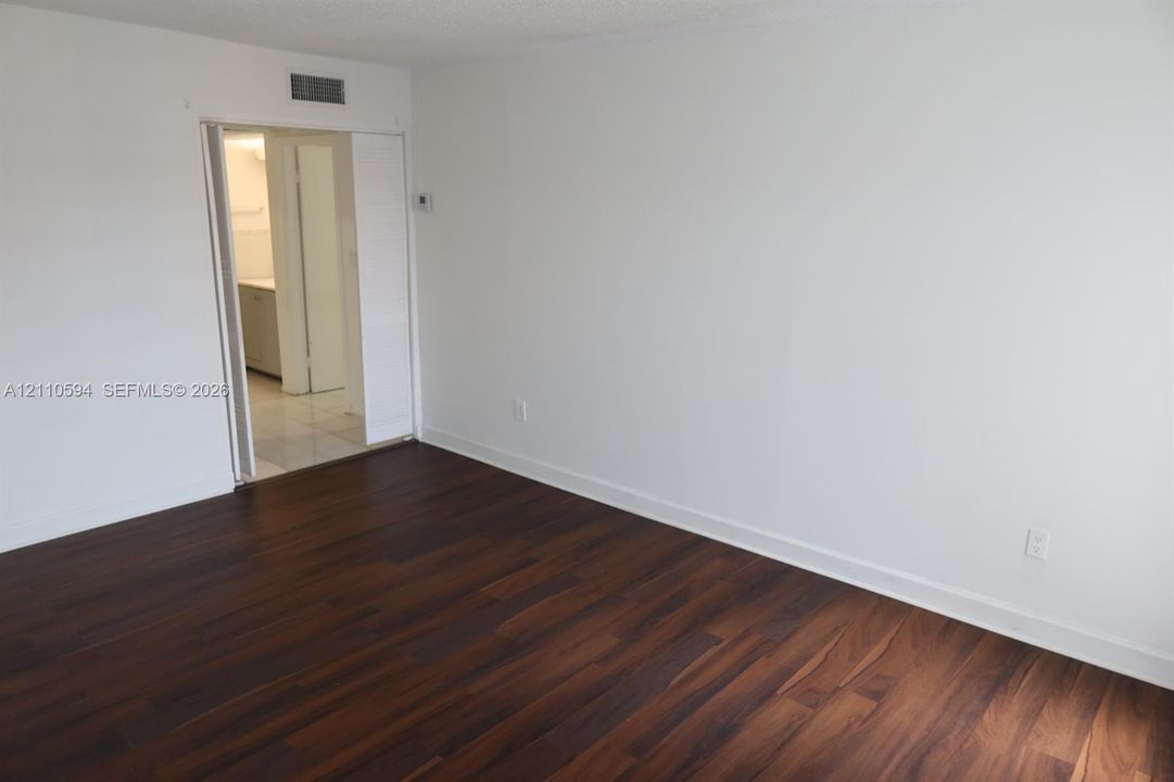 Interior space featuring dark wood-finish flooring, neutral white walls, and a sliding-door entry