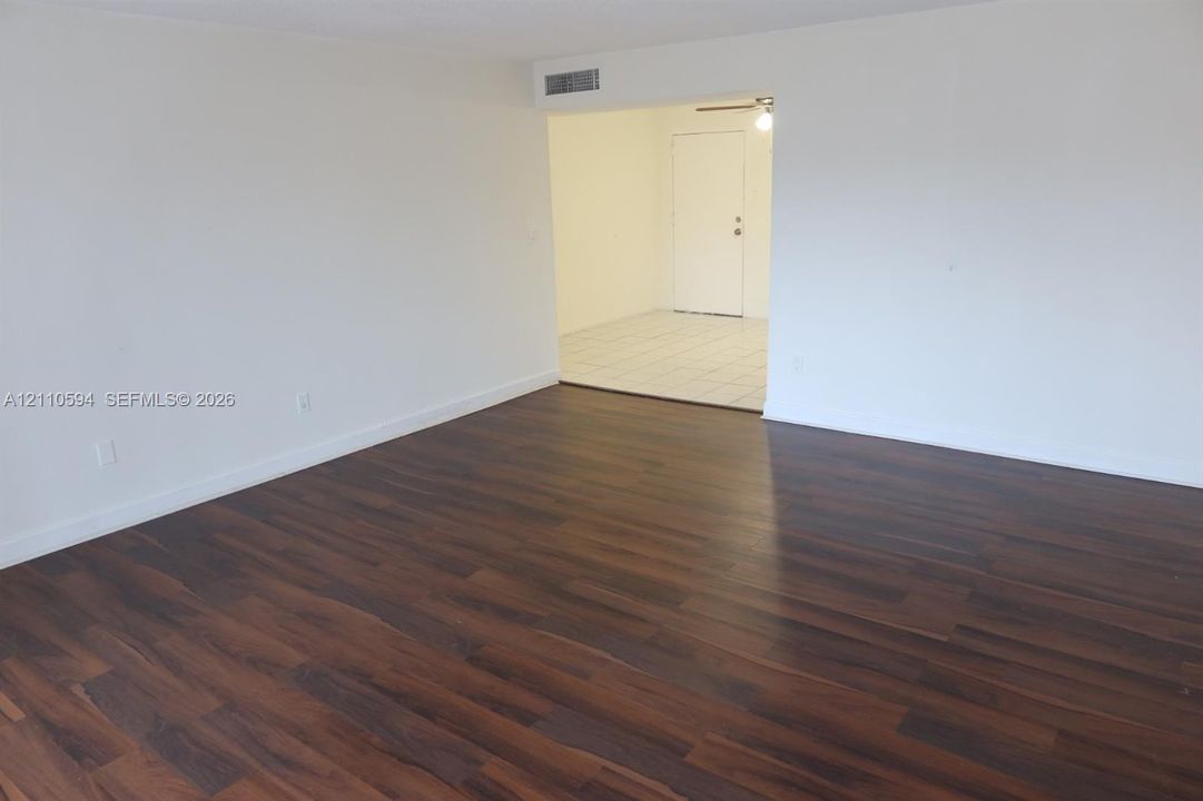 Interior space featuring wood-finish flooring and neutral-toned wall paint, with a separate area finished with light-colored tile flooring