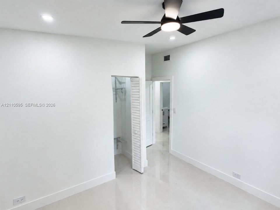 Neutral-toned flooring, recessed ceiling lighting, and a modern black matte ceiling fan with integrated illumination