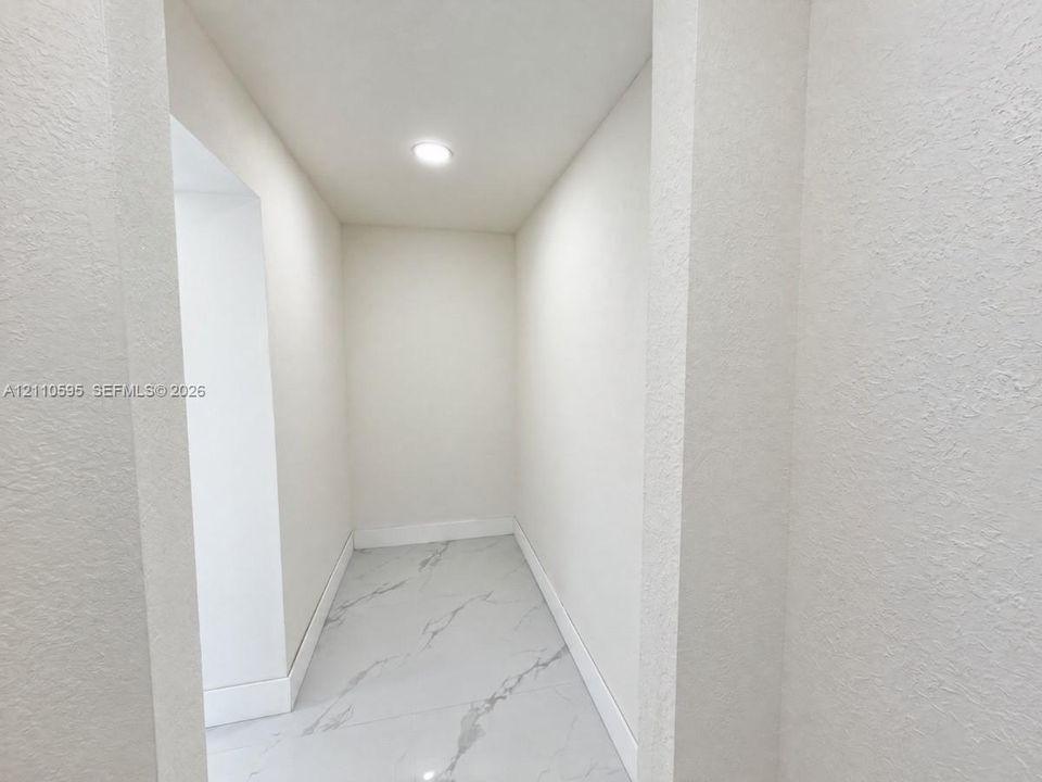 Neutral wall finishes, recessed ceiling lighting, and large-format stone-finish floor tiling with veining detail