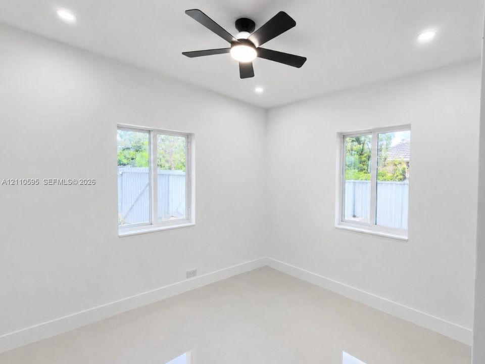 Room featuring neutral wall finishes, recessed lighting, a modern ceiling fan, and sliding windows