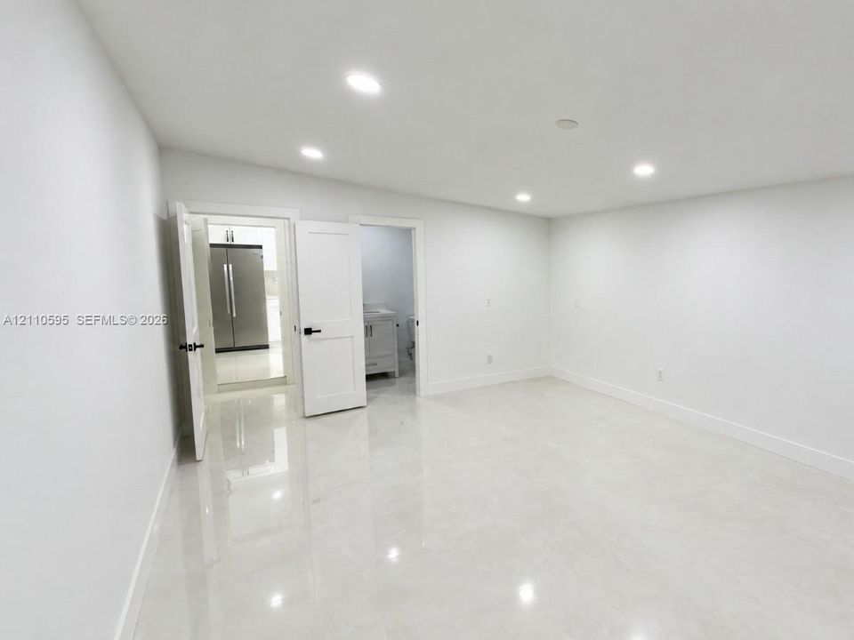 Interior space featuring polished stone-finish flooring, recessed lighting, and white shaker-style doors with matte black hardware